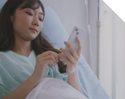 Female patient laying in bed, watching something on her phone